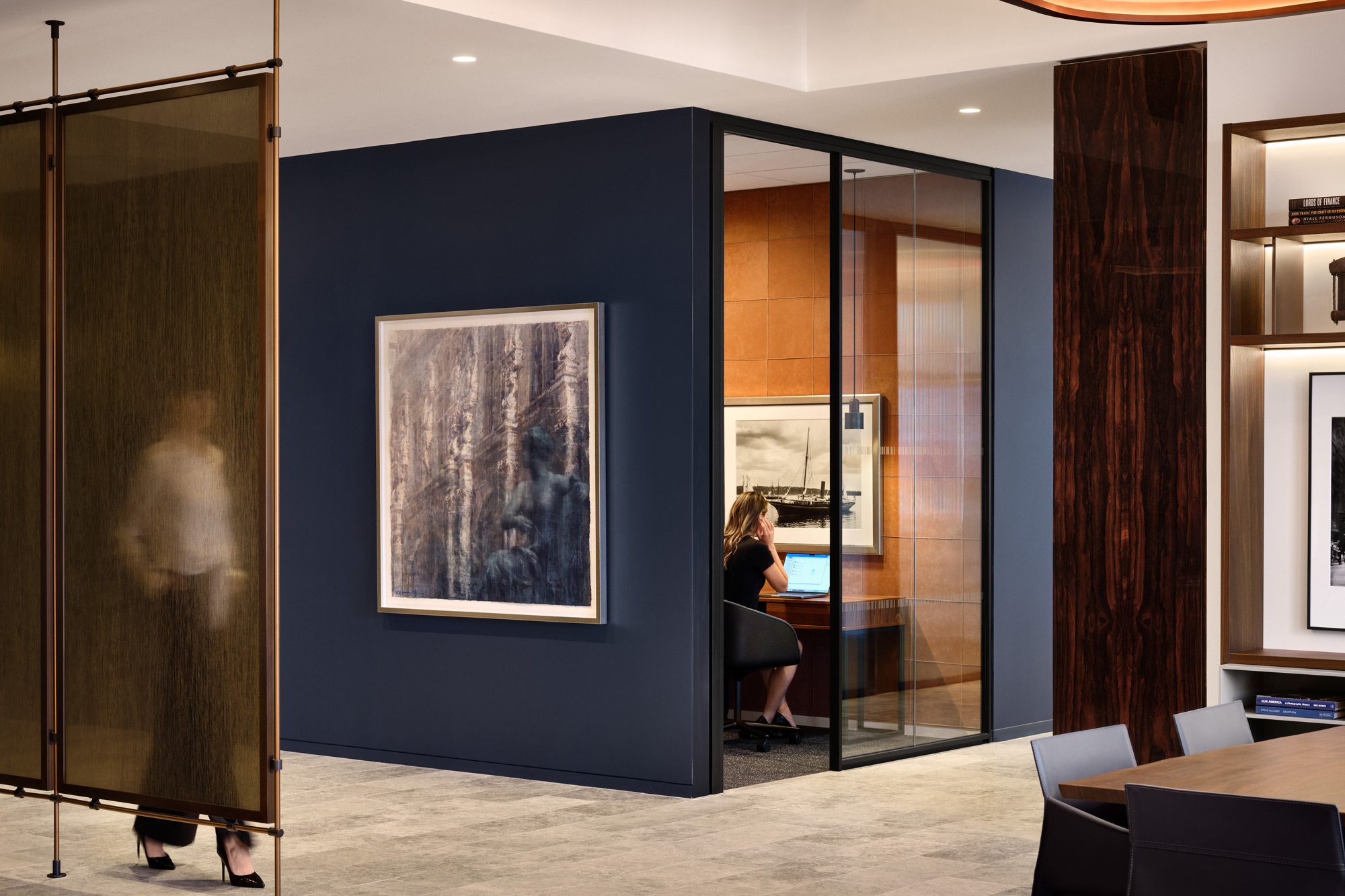 A person sitting at a desk in a room with a large glass door.