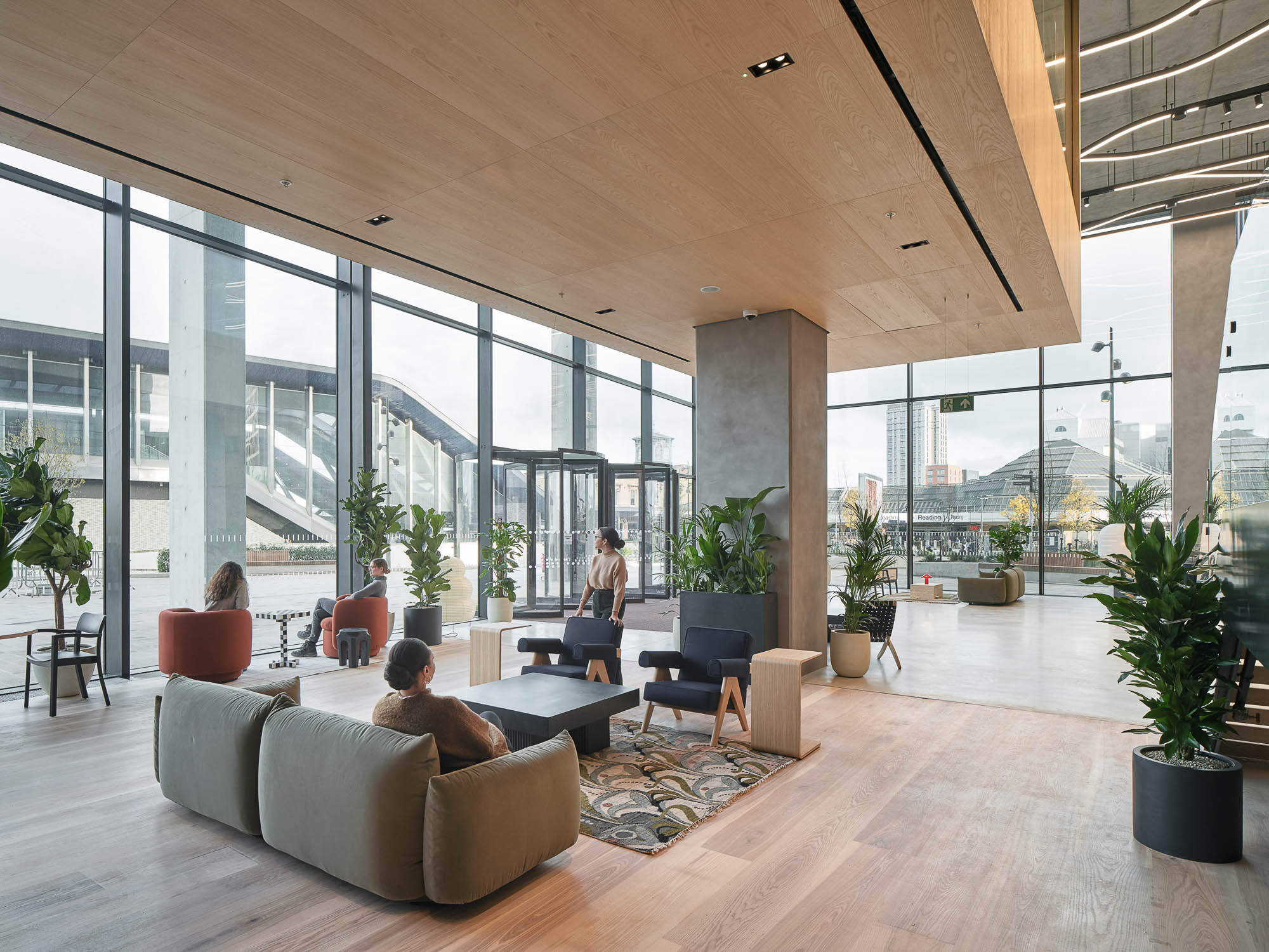 A man and woman sitting on a couch in a large room with large windows.