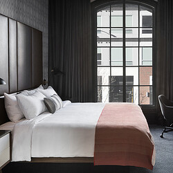 A bed with a pink comforter.