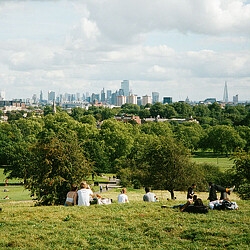 A group of people sitting on a grassy hill overlooking a city.