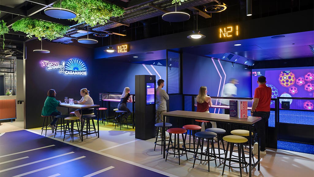 A group of people sitting at tables in the TOCA Social sports venue.