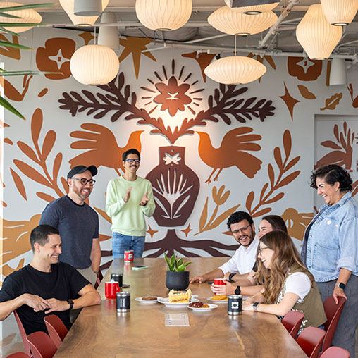 A group of people sitting around a table with food and drinks.