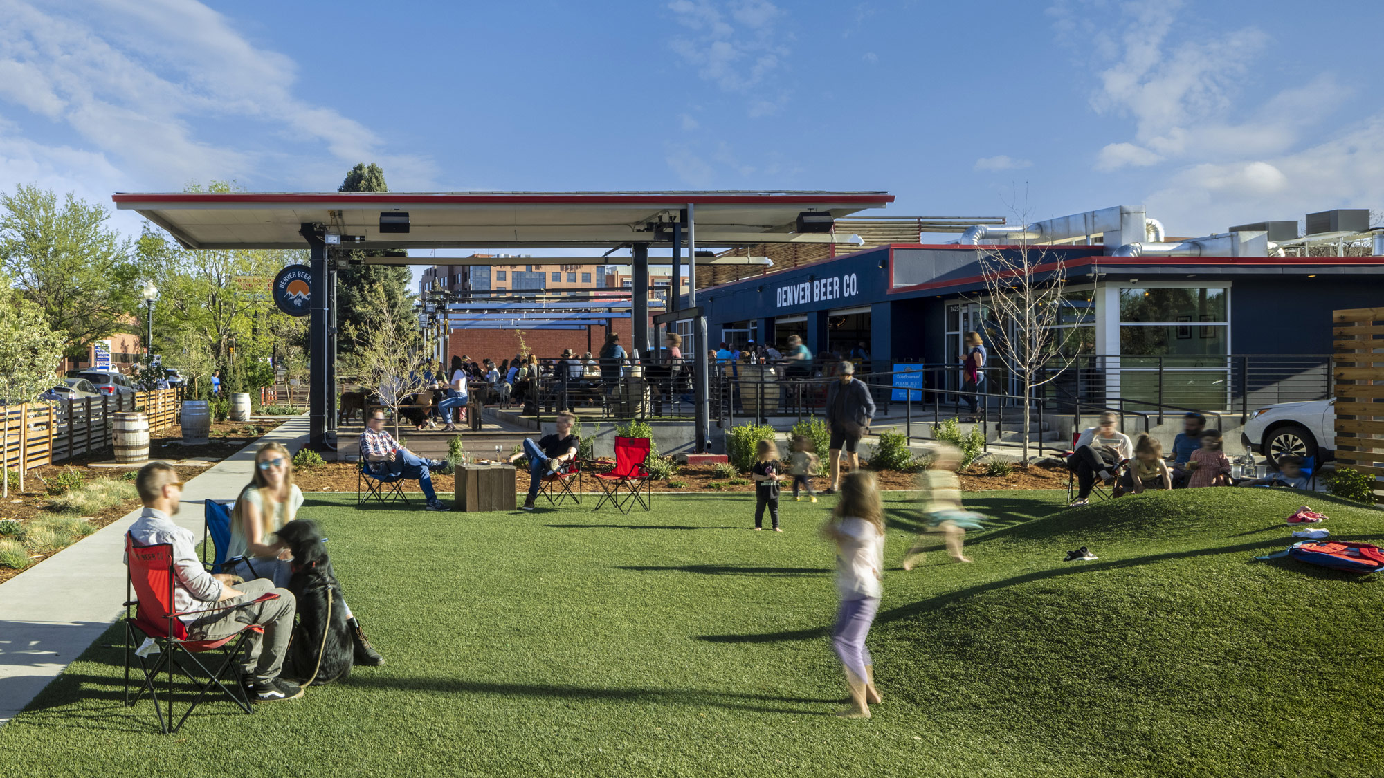 A group of people playing in a grassy area with a building in the background.
