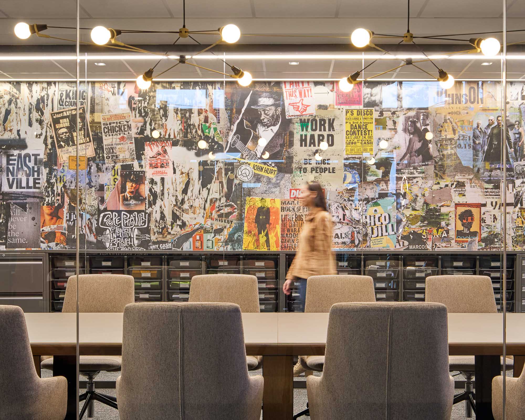 Woman walking down hall in Officeworks Nashville showroom with wall covered in posters