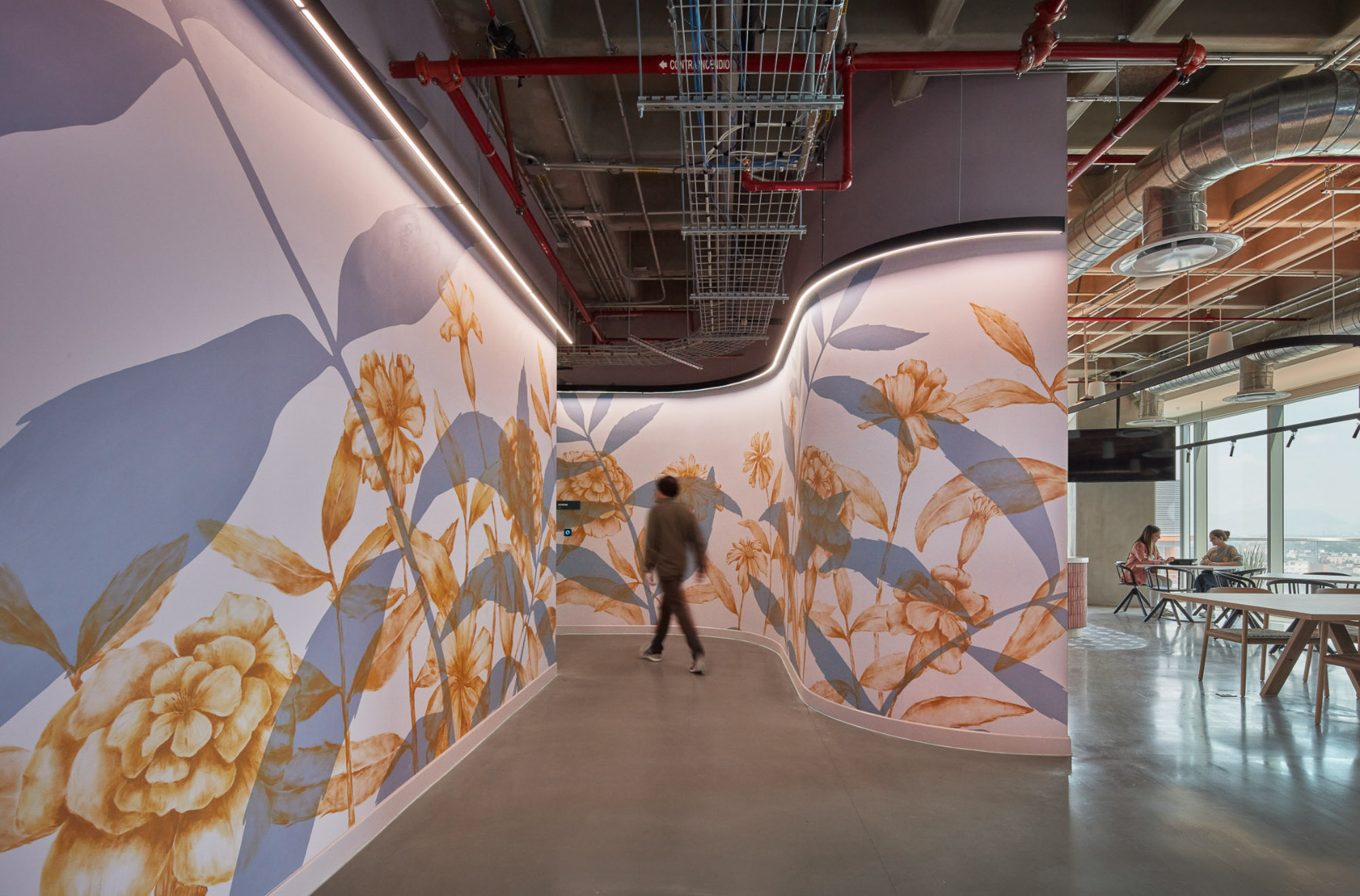 A person walking in a large room with a large piece of art.