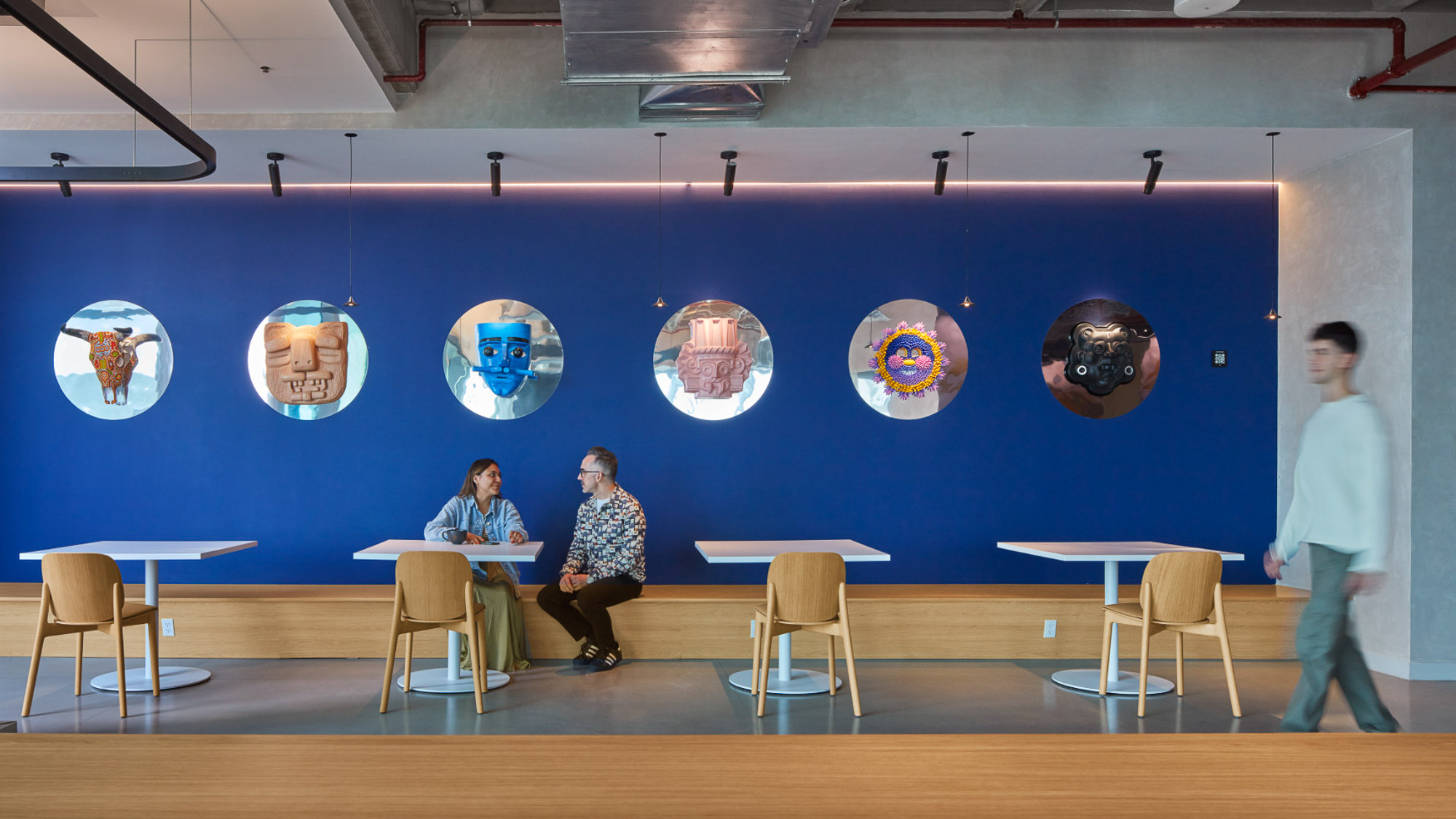 A group of people sitting at a table in front of a blue wall.