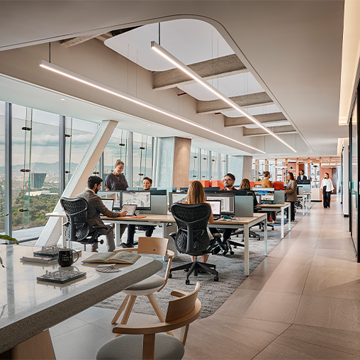 A group of people sitting at tables in a room with windows.