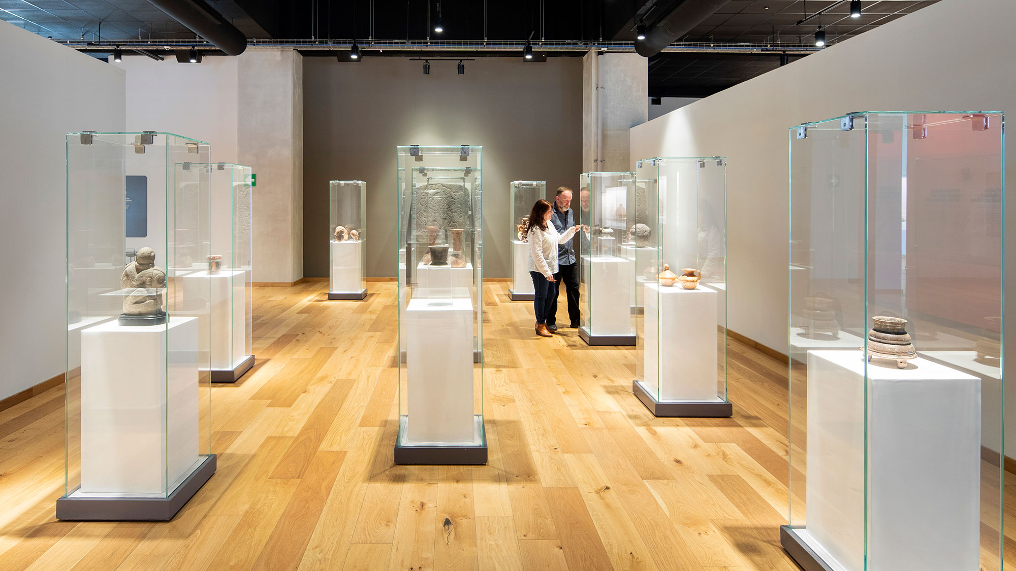 A couple of people standing in a room with glass display cases.