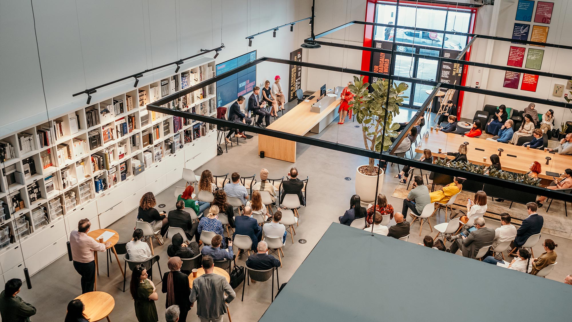 A group of people sitting in a room with a stage and a large group of people.